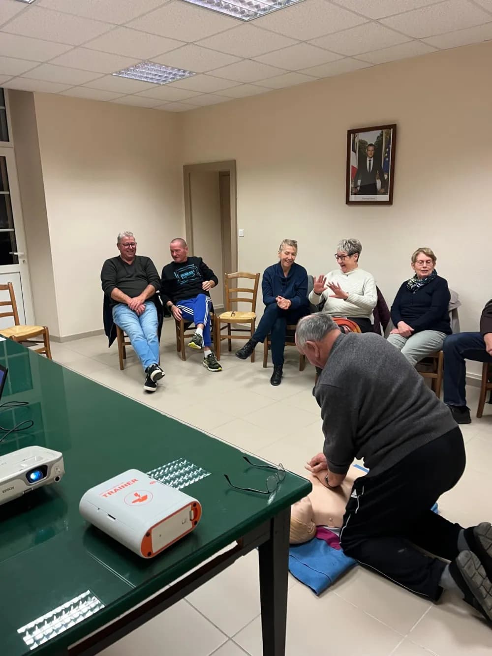 Démonstration de massage cardiaque sur mannequin face à un groupe en formation